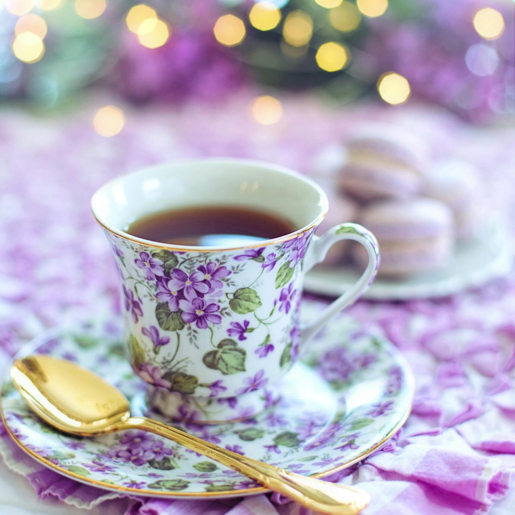 Charming floral teacup with a golden spoon, perfect for a serene teatime with macarons.
